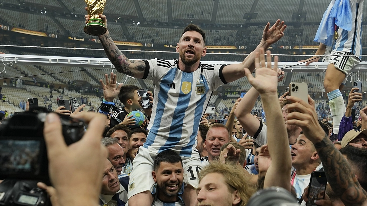 Lionel Messi sits on his teammates shoulders, lifting the World Cup